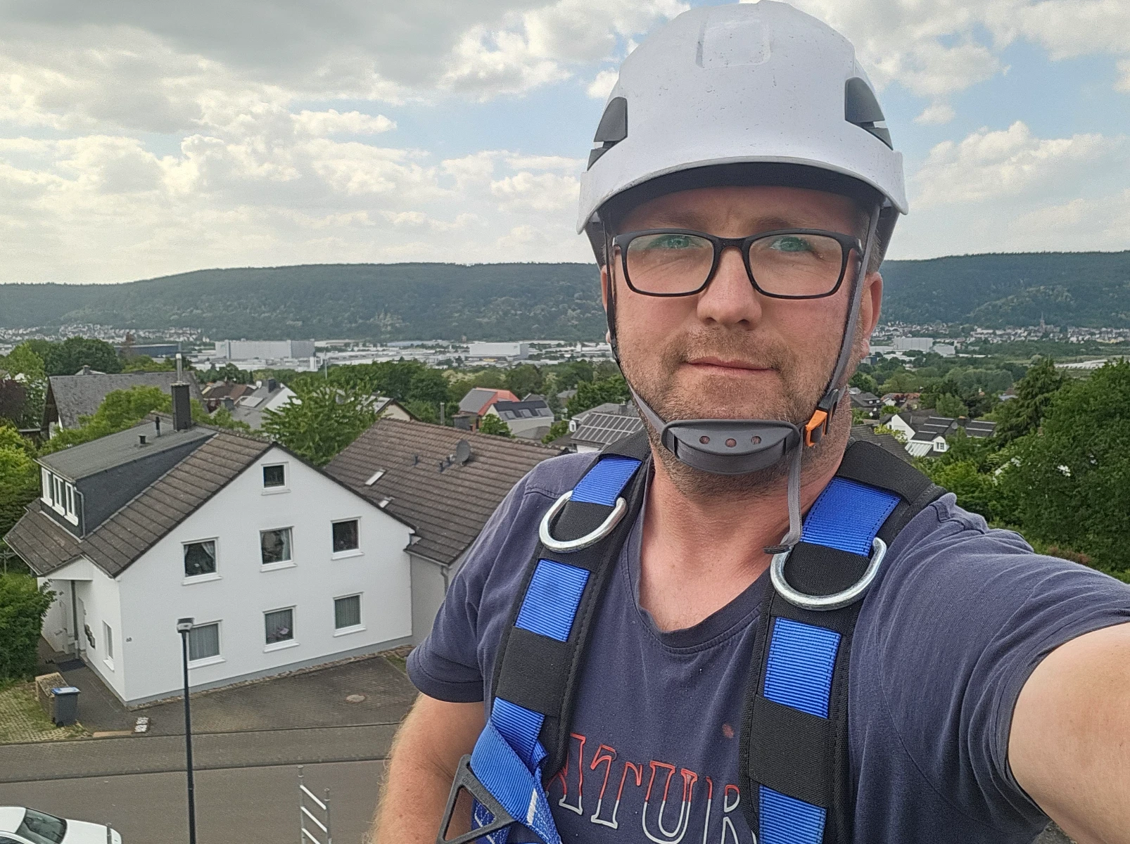 Technicien en harnais et casque se tenant sur un toit pour préparation au nettoyage du toit